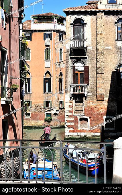 Vertical image of a canal with a gondola sailing by in Venice, Italy