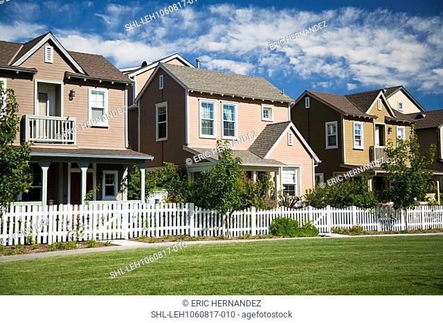 Row of homes in housing community with white picket fence