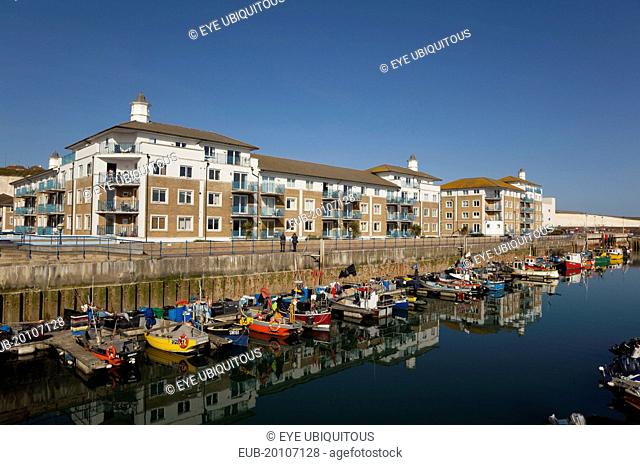 View over fishing boats moored in the Marina with apartment buildings behind