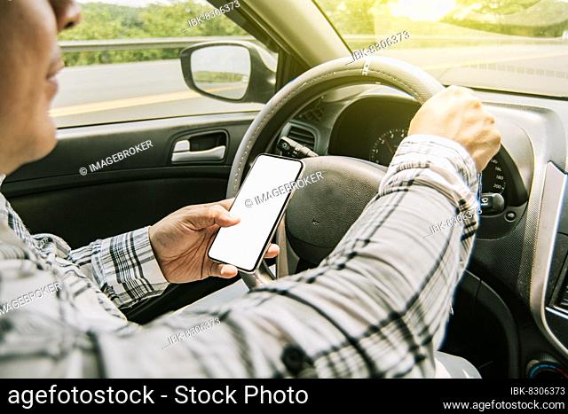 Man using his phone while driving, Person holding the cell phone and with the other hand the steering wheel, Concept of irresponsible driving