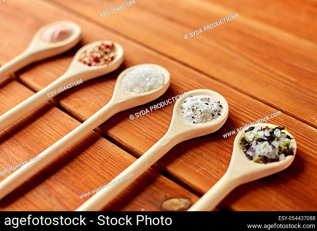 spoons with salt and spices on wooden table