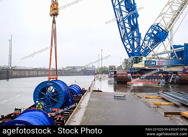 20 October 2023, Saxony-Anhalt, Magdeburg: A crane lifts a cable drum from a ship in the industrial port of Magdeburg. The underground cable on the cable drum...