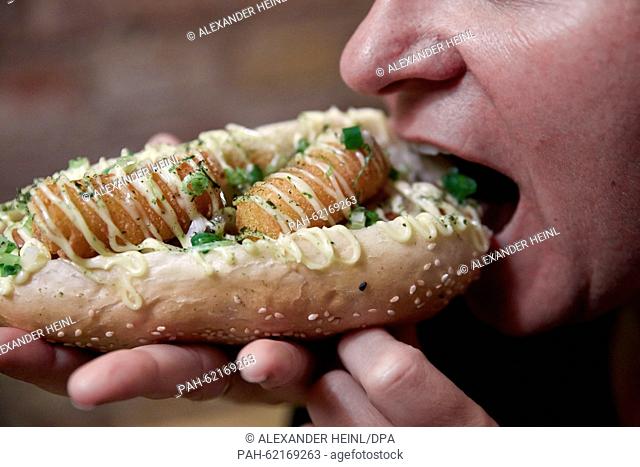 A woman bites into a hot dog with the name 'Japan-s Darling' at the restaurant 'OiShii Hot Dog' in Berlin, Germany, 25 September 2015