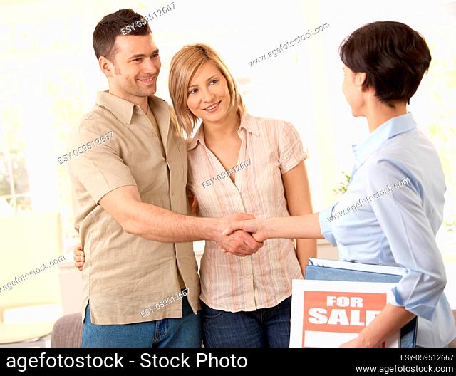 Estate agent congratulating young couple on making deal on new house