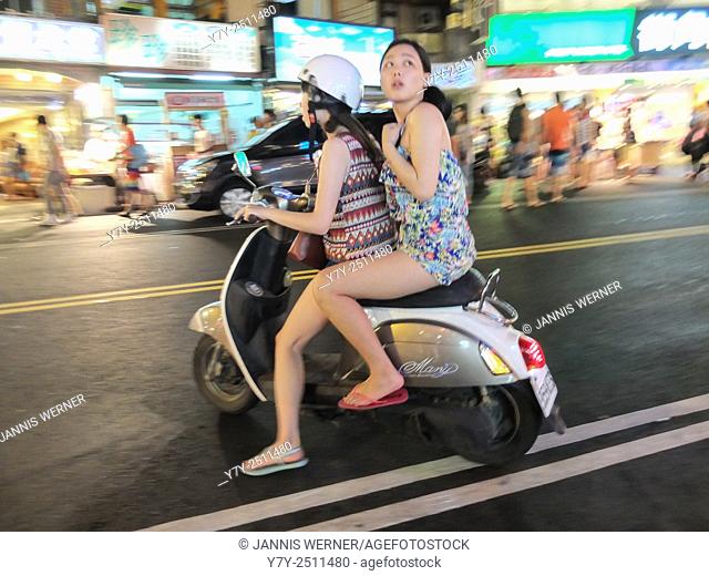 Girls riding a scooter on a night market in Taiwan