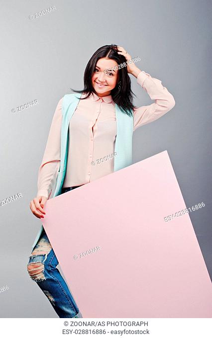 Full length studio portrait of young girl model at ripped jeans and rose blouse with pink banner board