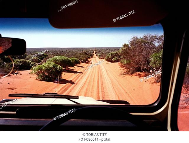 A view of a desert road in Australia through the windshield of an off-road vehicle