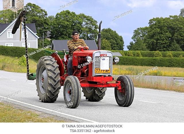 Kimito, Finland. July 6, 2019. Man drives Valmet 361 D tractor, year 1962, in front of farm equipment on Kimito Tractorkavalkad, vintage tractor parade