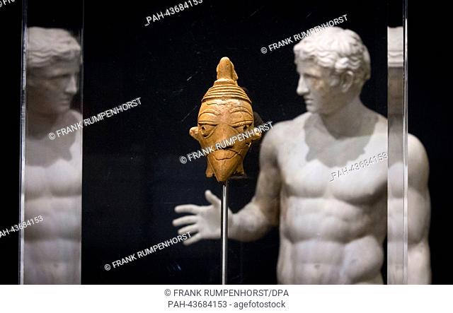A terracotta head (800-400 BC) in front of a Roman replica of a Greek sculpture of a discus thrower from 500 BC seen during the preview of the exhibition 'Nok