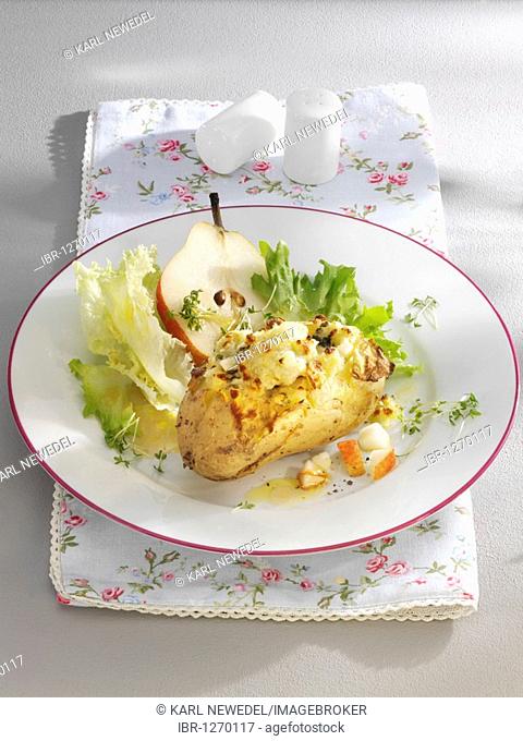 Au gratin potatoes with a pear and salad on a plate with a floral napkin and salt and pepper shakers