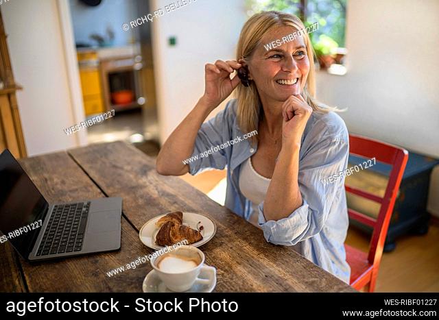 Woman playing with fruit sitting by table at home