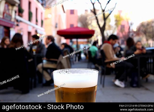 PRODUCTION - 11 December 2021, Spain, Madrid: Customers sit on the terrace of a bar in the center of Madrid. Although the Corona numbers are also on the rise...