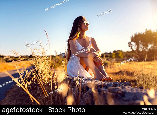 Woman in her vacation sitting on a stone wall in rural Alentejo, Portugal during the evening