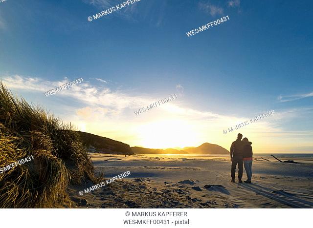 New Zealand, South Island, Puponga, Wharariki Beach, Couple on the beach at sunset