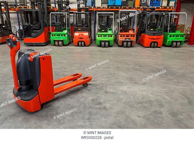 Mechanical dolly and forklift machinery in warehouse