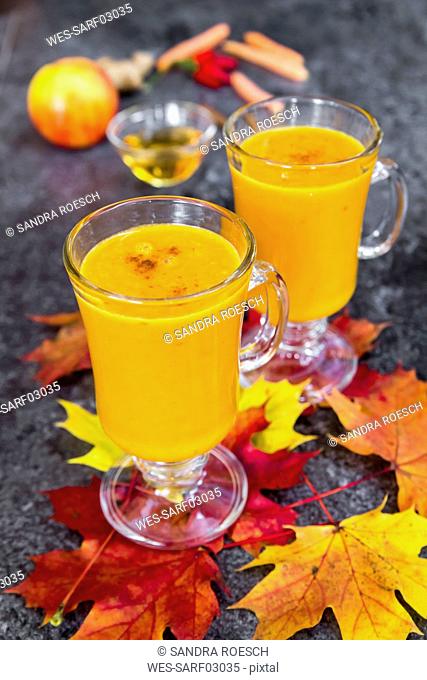 Two glasses of pumpkin smoothie and autumn leaves