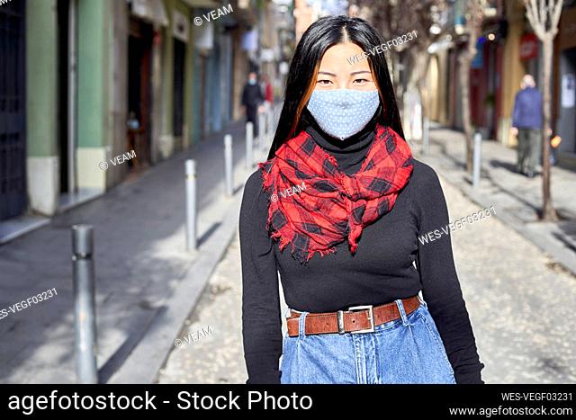 Young woman wearing protective face mask standing on street in city