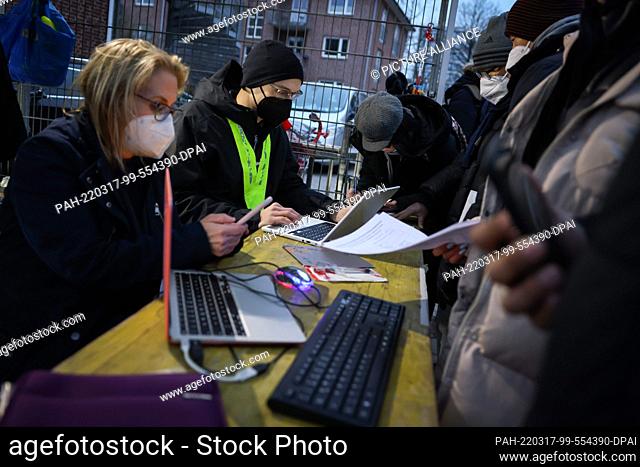 17 March 2022, Hamburg: Jennifer (l), a teacher from Hamburg, and Nathan, a student, use their computers to help fill out online applications in front of the...