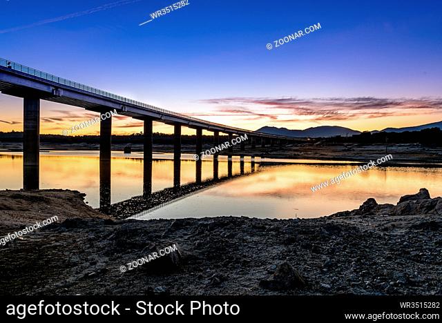 Silhouette Of Bridge Over river at sunset with reflections on water