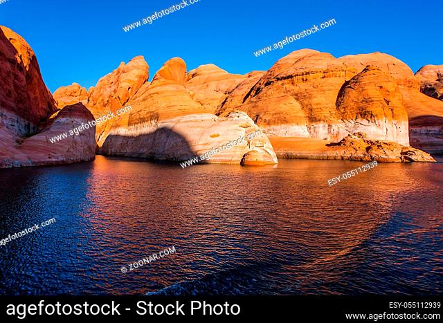 Sunset. Grandiose cliffs - red sandstone outcroppings. Tour on a tourist boat on an artificial reservoir Lake Powell. The Colorado River and Antelope Canyon