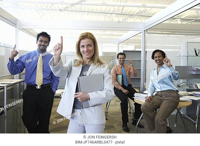 Group of coworkers making the Number One hand gesture