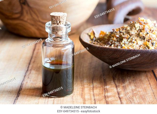 A bottle of myrrh essential oil with myrrh resin in the background