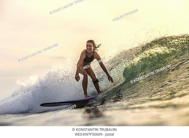 Indonesia, Bali, woman surfing at sunset