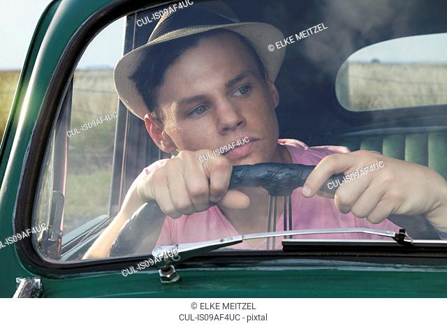 Young man looking through windscreen of vintage morris minor