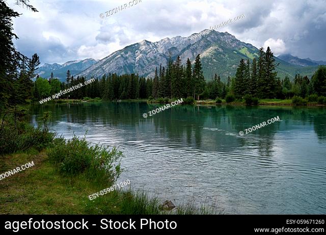 Panoramic image of the tranquil Bow river close to Banff with cloudy sky, Banff National Park, Alberta, Canada