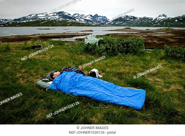 Norway, man sleeping outdoors in sleeping bag