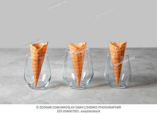 Sweet crispy wafer hornes for dessert in a glass vases on a gray marble background with copy space