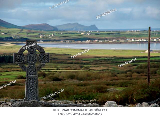 Celtic cross with irish landscape and cloudy sky