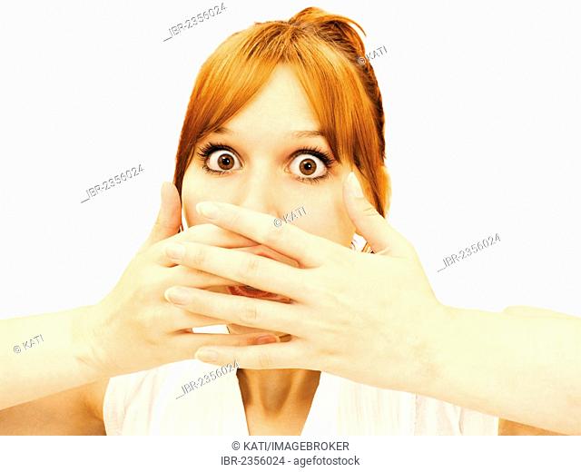 Frightened young woman holding both hands over her mouth