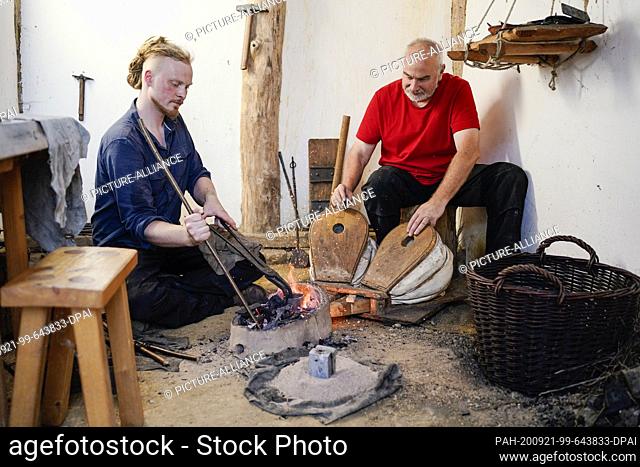 15 September 2020, Hessen, Lorsch: The metal designers Pierre Stoll (l) and Frank Trommer work on a fireplace in the Lauresham open-air laboratory