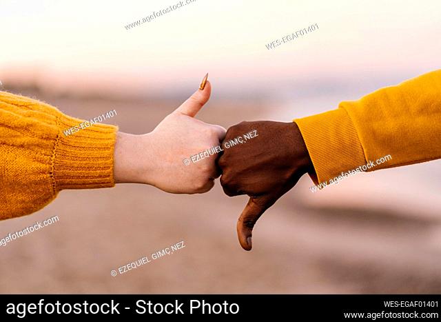 Man and woman gesturing with thumps up and down at beach
