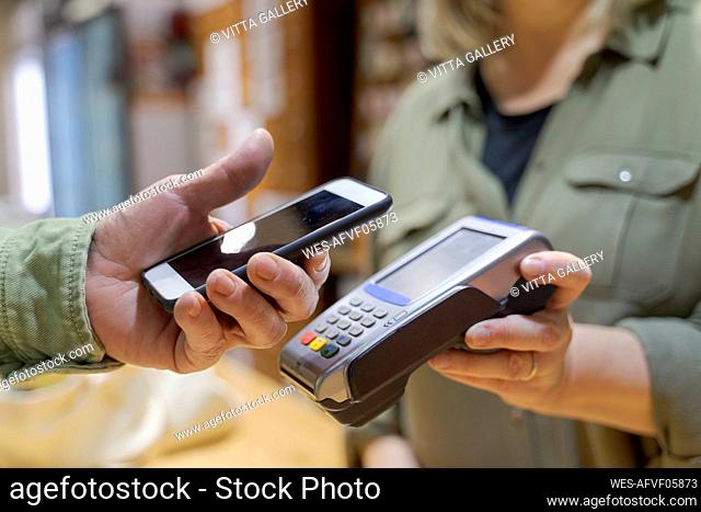 Customer paying contactless with smartphone in a shop