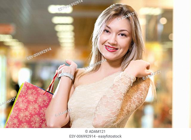 portrait of a beautiful woman in a shopping center, holding shopping bags and smiling