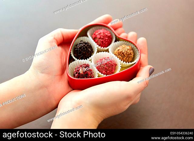 hands with candies in heart shaped chocolate box