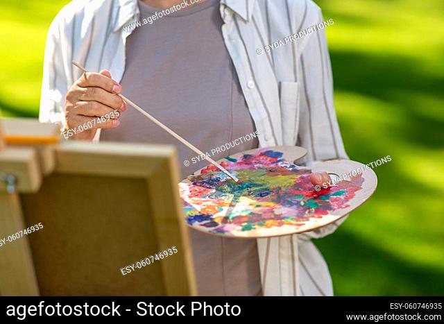 close up of woman with easel painting outdoors