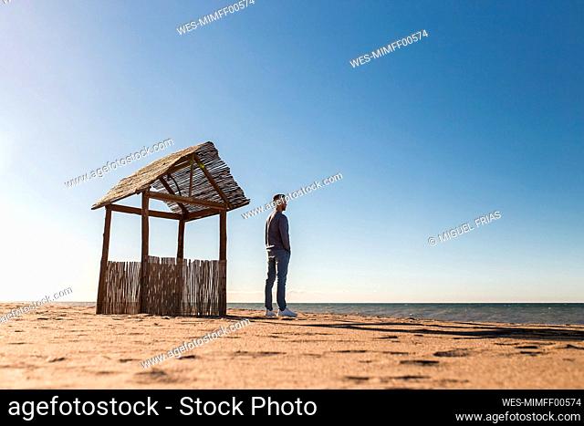 Man looking at sea view while standing on beach during sunny day