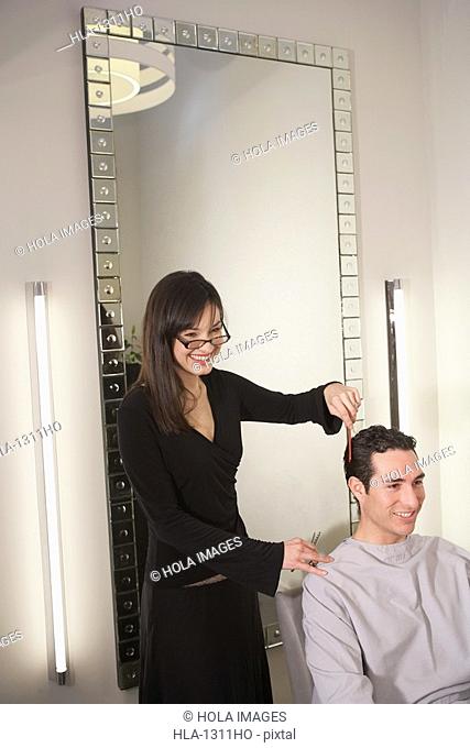 Side profile of a female hairdresser cutting hair of a mid adult man