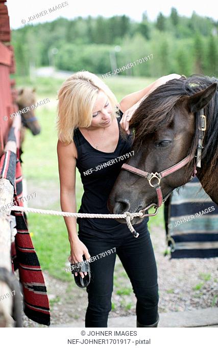Young woman brushing horse