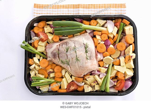 Raw leg of lamb and vegetable in roasting tray, elevated view