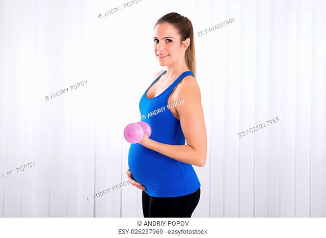 Happy Pregnant Woman Doing Exercise In Sports Hall