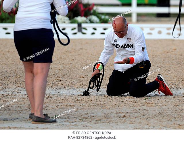 Team support member Robbie Sanderson of Germany falls to the floor after being kicked by horse Cosmo of German rider Soenke Rothenberger during the medal...
