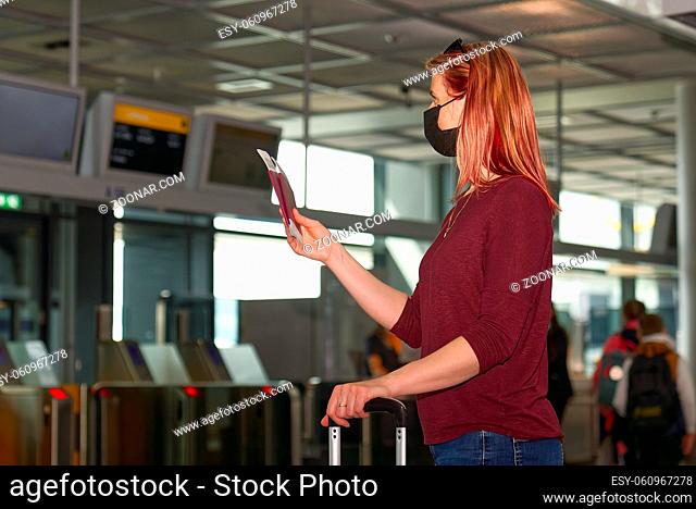Young woman with protective face mask, passport and airline fly tickets at the international airport. Safe travel during the COVID 19 pandemic concept