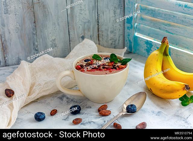 Chocolate smoothie bowl with cocoa beans, blueberry, granola and seeds for healthy breakfast, selective focus
