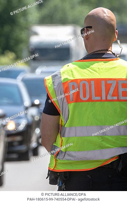 15 June 2018, Germany, Pocking: A German police officer stands at a check point on highway A3 at the German-Austrian border. Photo: Armin Weigel/dpa