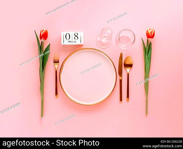 8 march table setting. Empty pink plate with gold cutlery, calendar with eight march date and red tulip on pink background