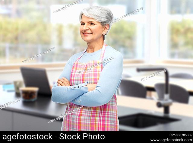 portrait of smiling senior woman in apron at home